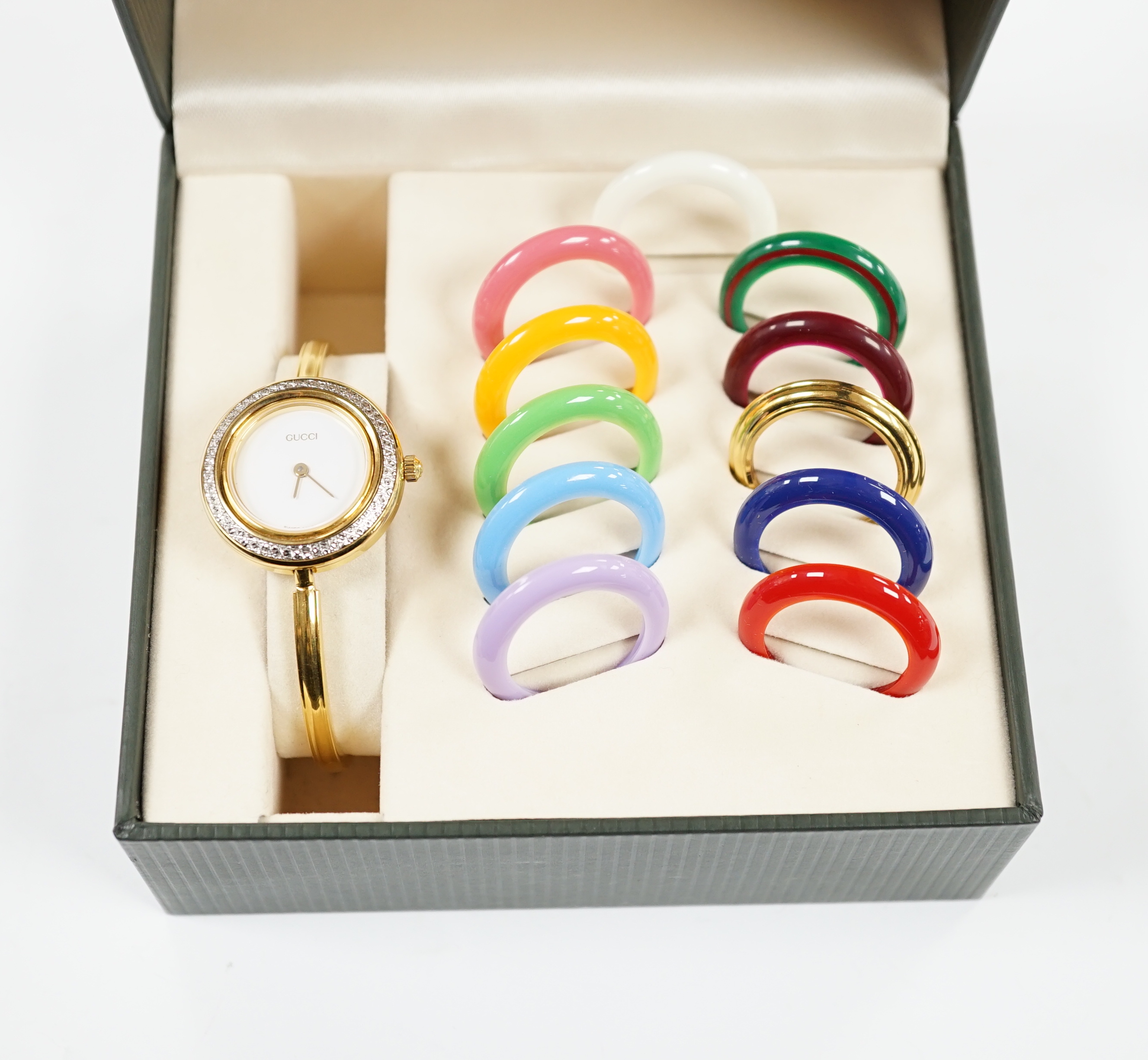 A lady's modern gilt Gucci quartz bangle wrist watch, with twelve interchangeable bezels, in original Gucci box.